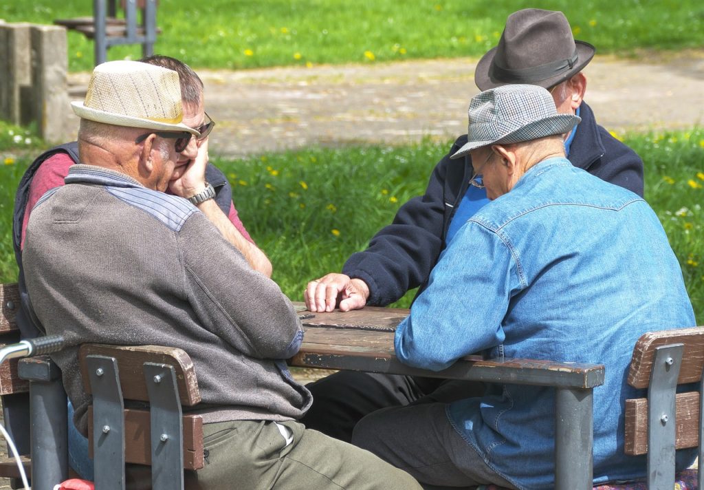 Neljä ikääntyvää miestä istuvat pöydän ääressä